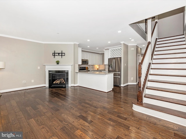 unfurnished living room featuring sink, crown molding, and dark hardwood / wood-style floors