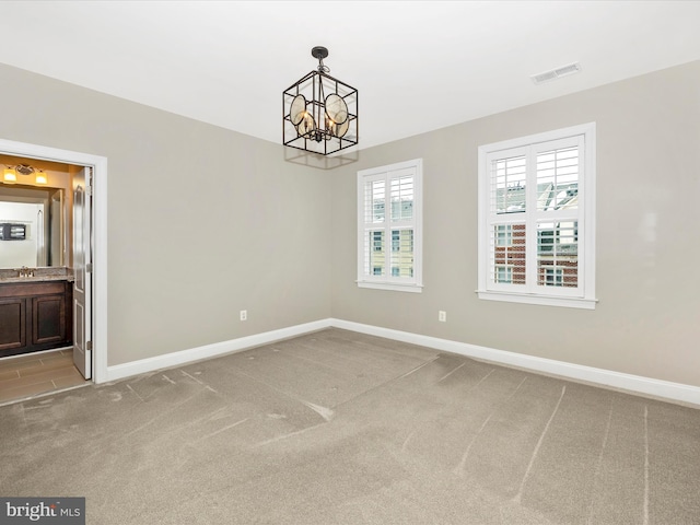 carpeted empty room featuring sink and a chandelier