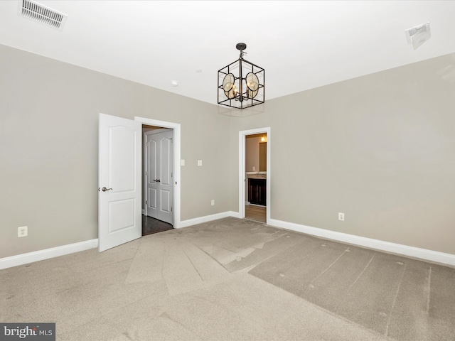 carpeted empty room featuring an inviting chandelier