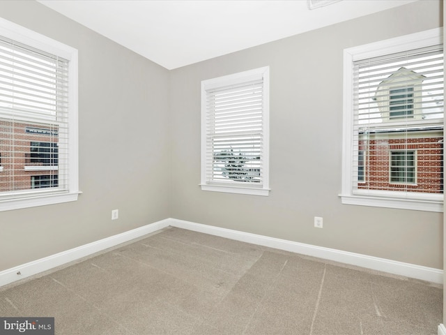 unfurnished room featuring plenty of natural light and carpet