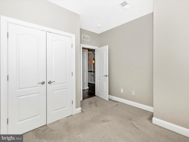 unfurnished bedroom with light colored carpet and a closet