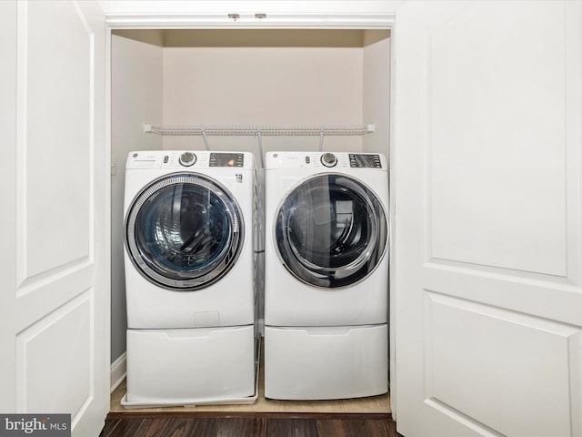 clothes washing area with dark wood-type flooring and washer and dryer