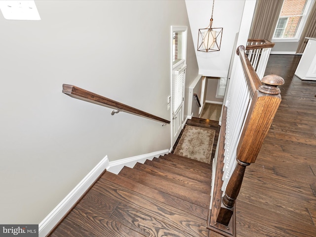 stairway with hardwood / wood-style flooring and an inviting chandelier