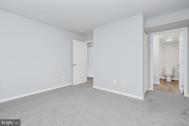 unfurnished bedroom with light colored carpet and ensuite bath