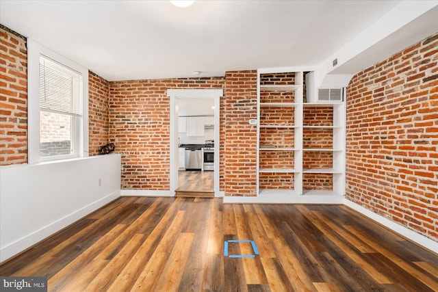 empty room with dark hardwood / wood-style flooring and brick wall