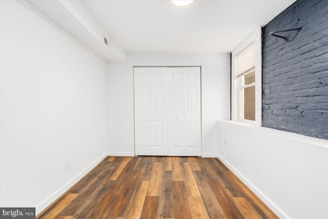 unfurnished bedroom with dark hardwood / wood-style flooring and a closet