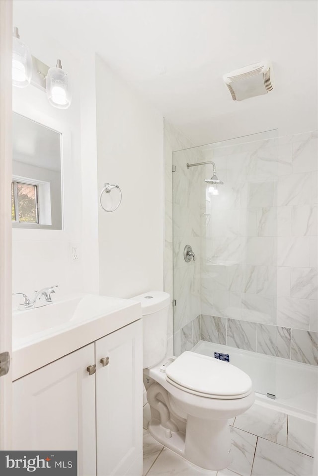 bathroom with vanity, toilet, and a tile shower