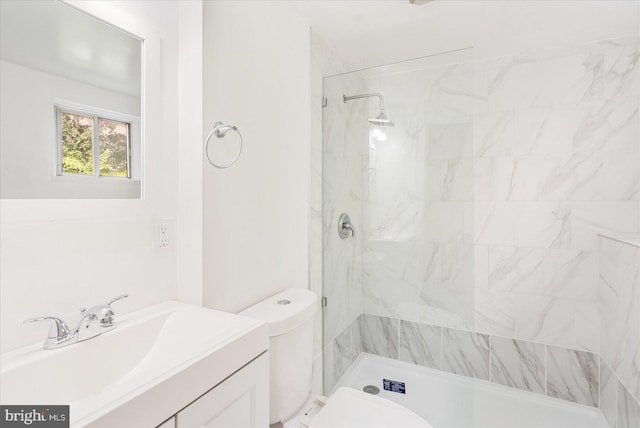 bathroom featuring tiled shower, vanity, and toilet