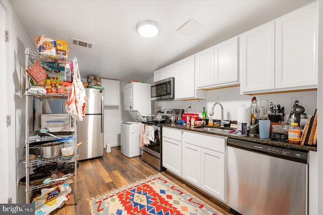 kitchen featuring dark stone counters, white cabinets, sink, dark hardwood / wood-style floors, and stainless steel appliances