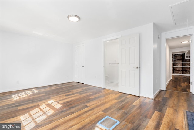 unfurnished bedroom with dark hardwood / wood-style floors, ensuite bathroom, and a closet