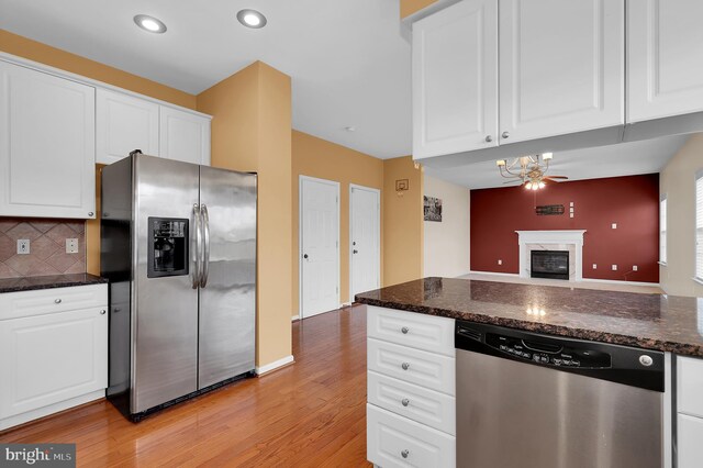 kitchen with backsplash, a high end fireplace, white cabinets, and appliances with stainless steel finishes