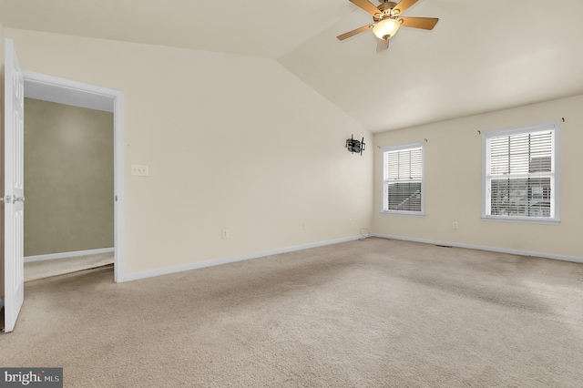 carpeted spare room featuring vaulted ceiling and ceiling fan