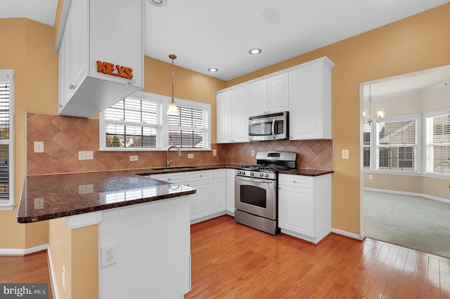 kitchen featuring white cabinets, hanging light fixtures, sink, appliances with stainless steel finishes, and kitchen peninsula