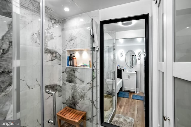 bathroom with hardwood / wood-style floors, vanity, toilet, and a shower with door