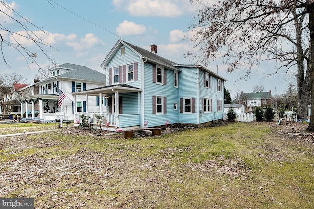 rear view of property with covered porch and a yard