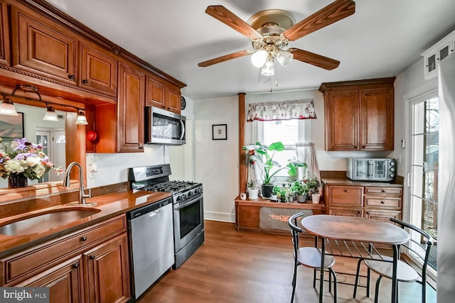 kitchen featuring appliances with stainless steel finishes, dark hardwood / wood-style flooring, ceiling fan, and sink