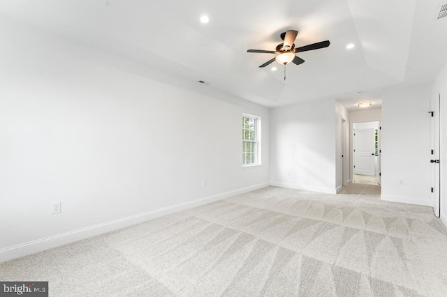 unfurnished room featuring a tray ceiling, ceiling fan, and light colored carpet