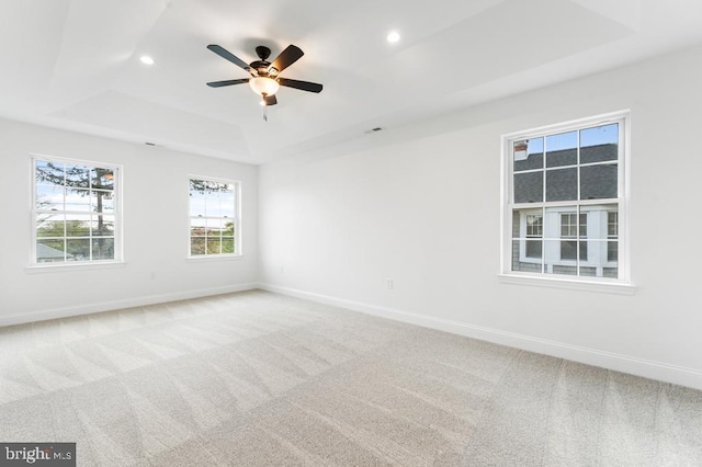 unfurnished room featuring a raised ceiling, ceiling fan, and carpet