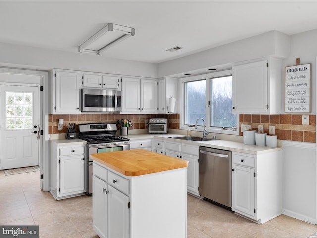 kitchen featuring white cabinets, stainless steel appliances, a kitchen island, and sink