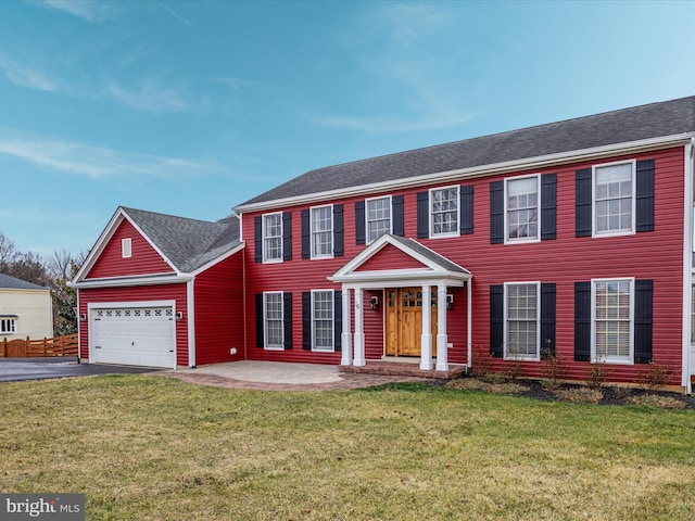 colonial inspired home featuring a garage and a front lawn