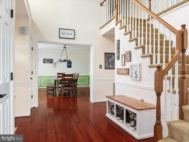 staircase with crown molding, a notable chandelier, and hardwood / wood-style flooring