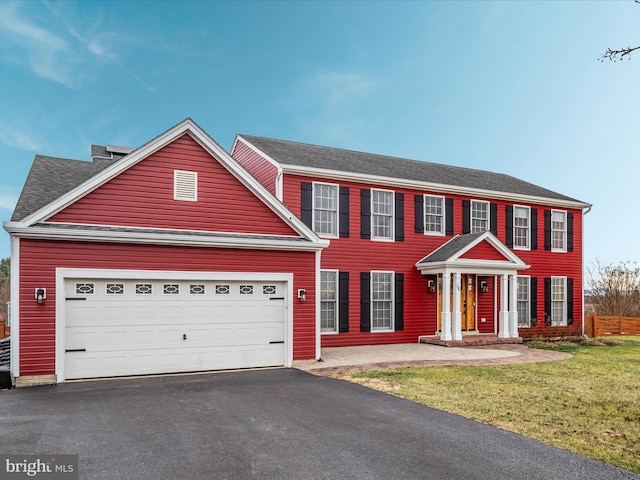 colonial inspired home featuring a garage and a front yard