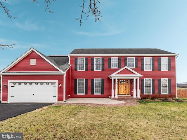 colonial inspired home featuring a garage and a front lawn