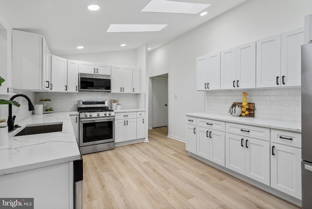 6136 Sinbad Pl, Columbia, MD 21045 - kitchen featuring stainless steel appliances, lofted ceiling with skylight, sink, and white cabinets