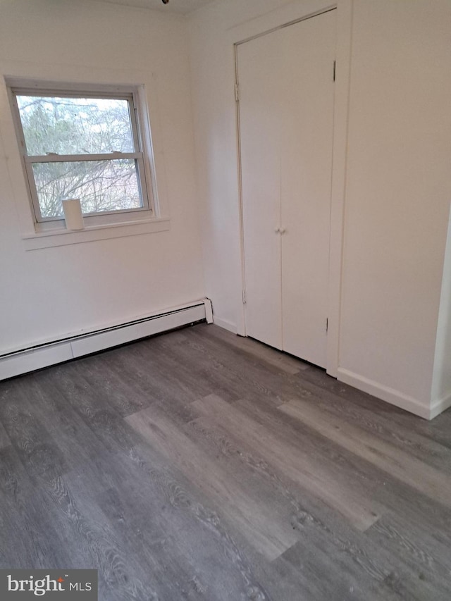 unfurnished bedroom featuring dark hardwood / wood-style floors and a baseboard radiator