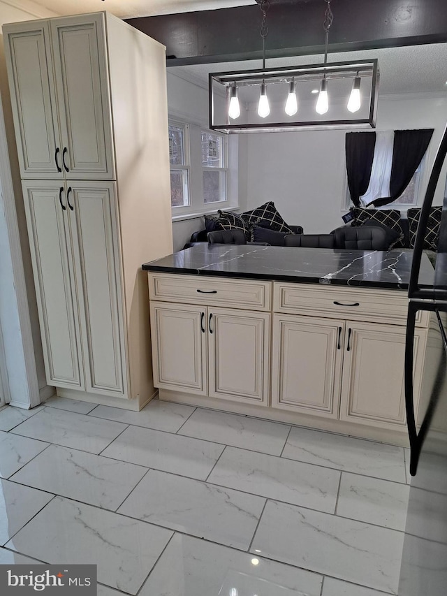 kitchen featuring cream cabinetry, pendant lighting, and dark stone countertops