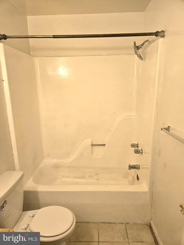 bathroom featuring tile patterned flooring, washtub / shower combination, and toilet