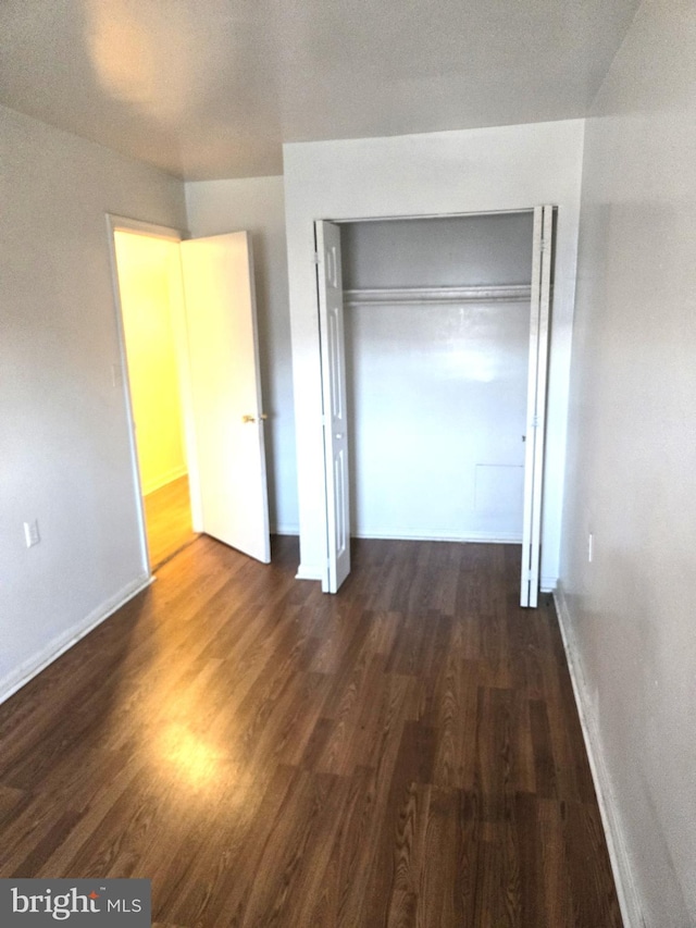 unfurnished bedroom with dark wood-type flooring and a closet