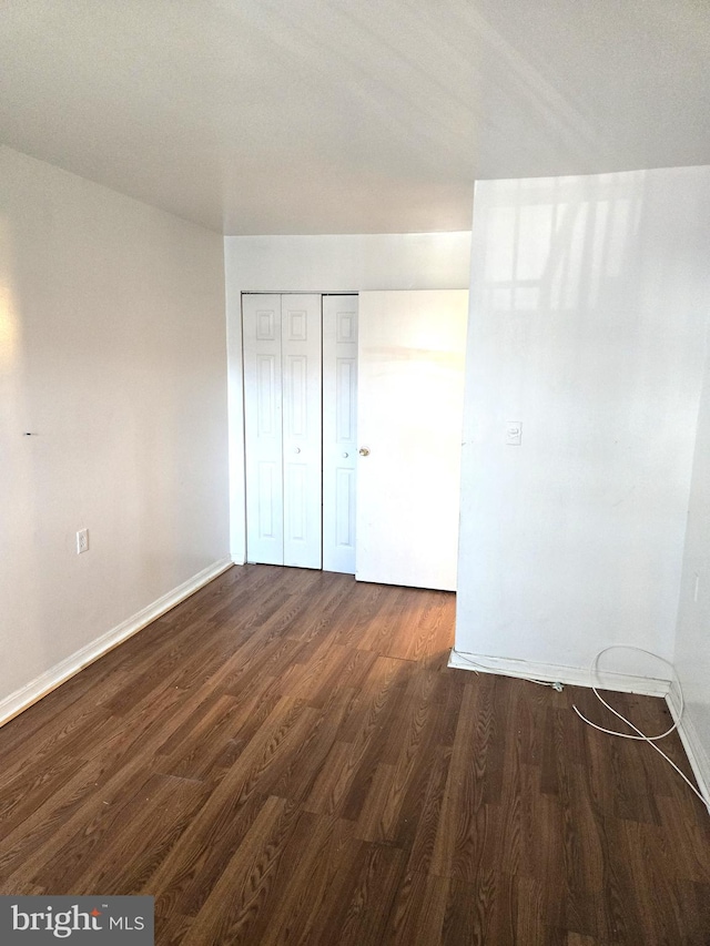 unfurnished bedroom featuring a closet and dark hardwood / wood-style flooring