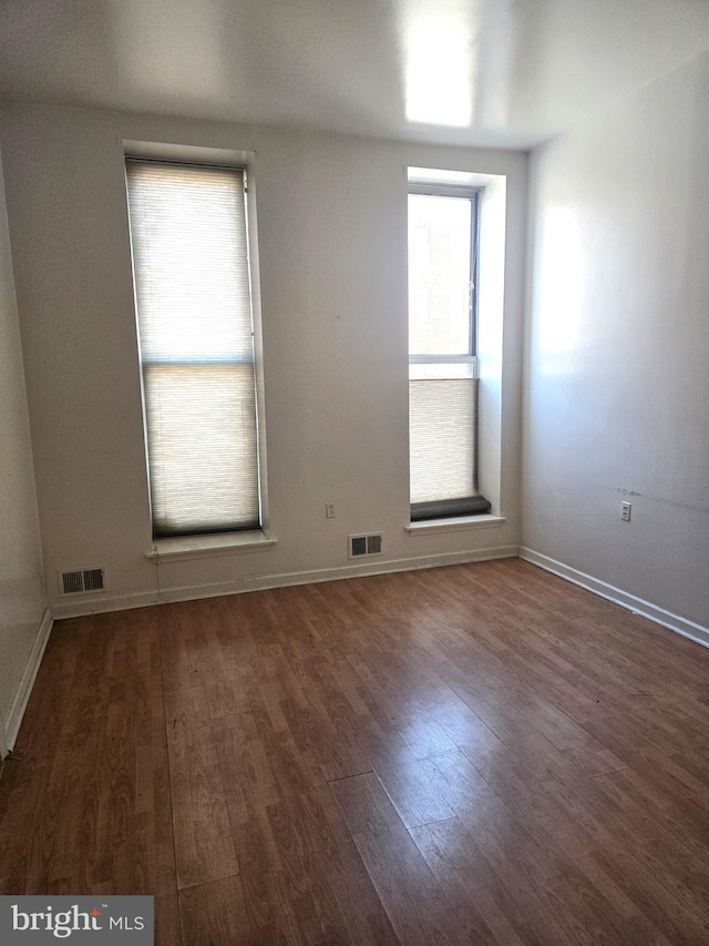 unfurnished room with dark wood-type flooring and a healthy amount of sunlight