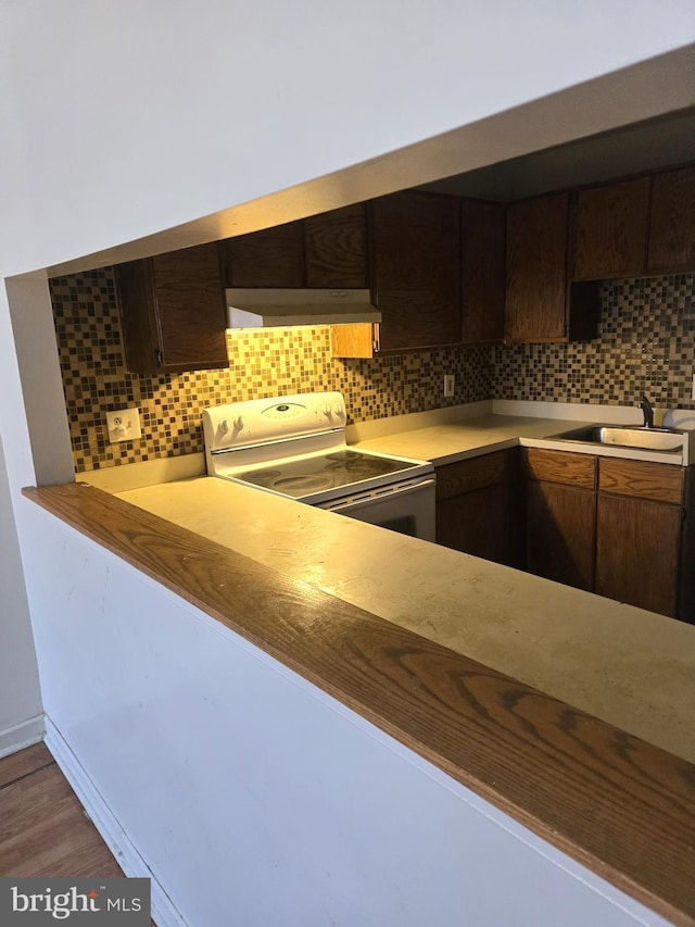 kitchen with backsplash, electric range, sink, and dark brown cabinets