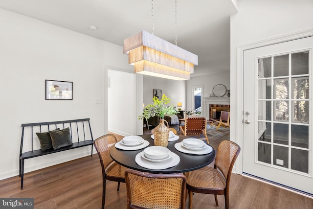 dining space featuring dark hardwood / wood-style flooring and a brick fireplace