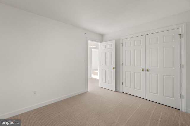 unfurnished bedroom with a closet and light colored carpet