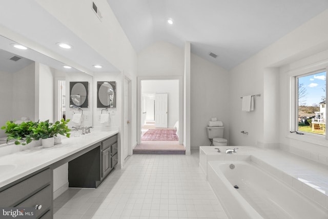 bathroom featuring vanity, a bath, vaulted ceiling, and toilet