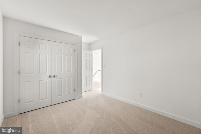 unfurnished bedroom featuring light carpet and a closet