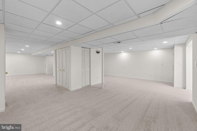 basement featuring a drop ceiling and light colored carpet