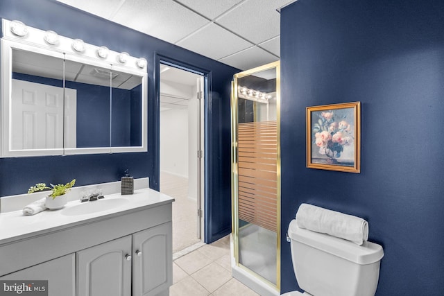 bathroom with a paneled ceiling, vanity, tile patterned flooring, toilet, and a shower with shower door