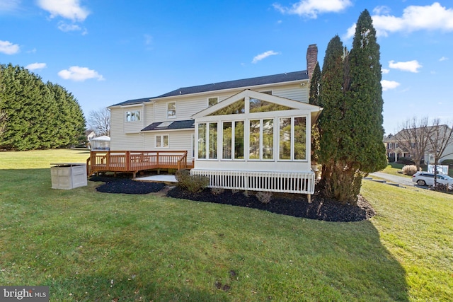 rear view of property with a sunroom, a yard, and a wooden deck