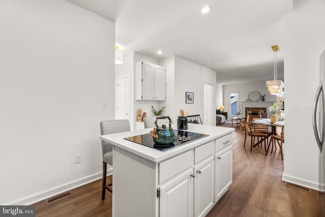 kitchen featuring white cabinetry, a breakfast bar, a kitchen island, and black electric stovetop