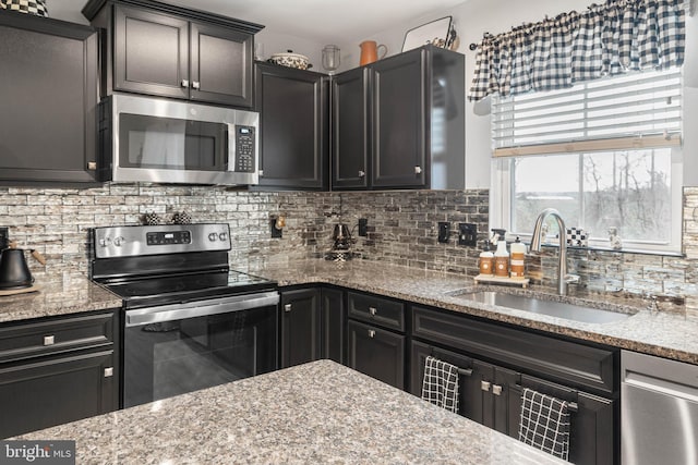 kitchen with light stone countertops, sink, appliances with stainless steel finishes, and tasteful backsplash