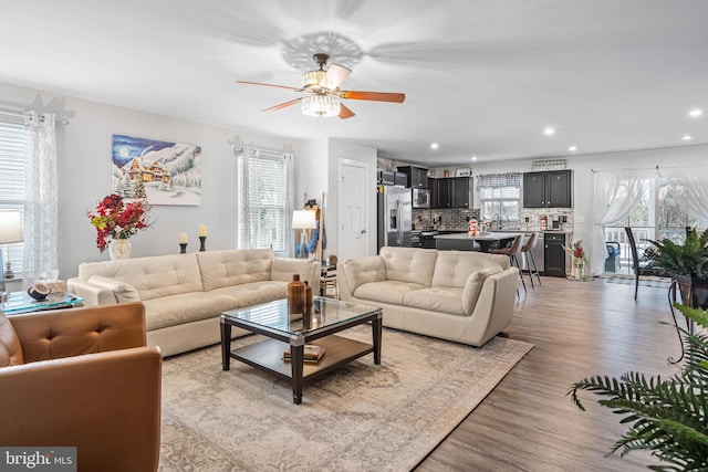 living room with plenty of natural light, ceiling fan, and light hardwood / wood-style flooring