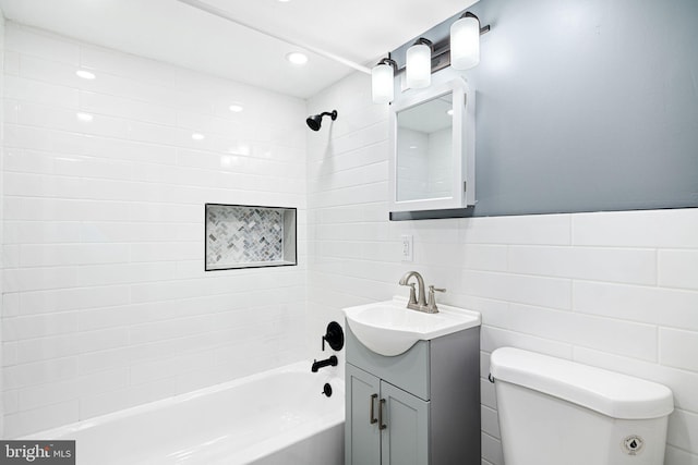 full bathroom with vanity, tiled shower / bath combo, tile walls, and toilet