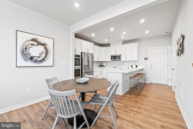 dining area featuring light wood-type flooring and sink