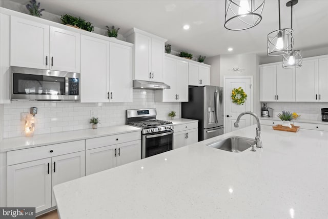 kitchen with white cabinets, decorative light fixtures, sink, and appliances with stainless steel finishes