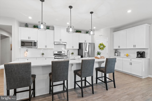 kitchen with decorative light fixtures, white cabinetry, an island with sink, and appliances with stainless steel finishes