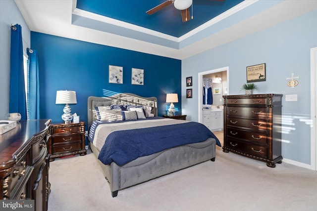 carpeted bedroom featuring a raised ceiling, ensuite bathroom, ceiling fan, and ornamental molding